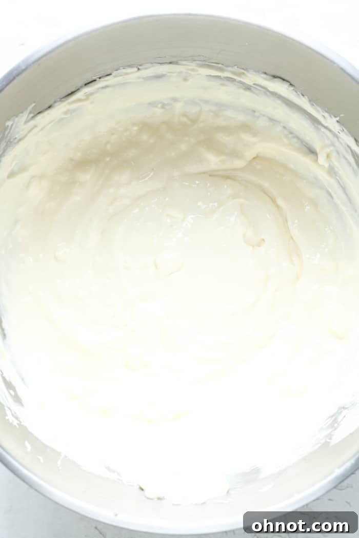 Silky smooth cheesecake batter after eggs have been gently incorporated, showing perfect consistency.