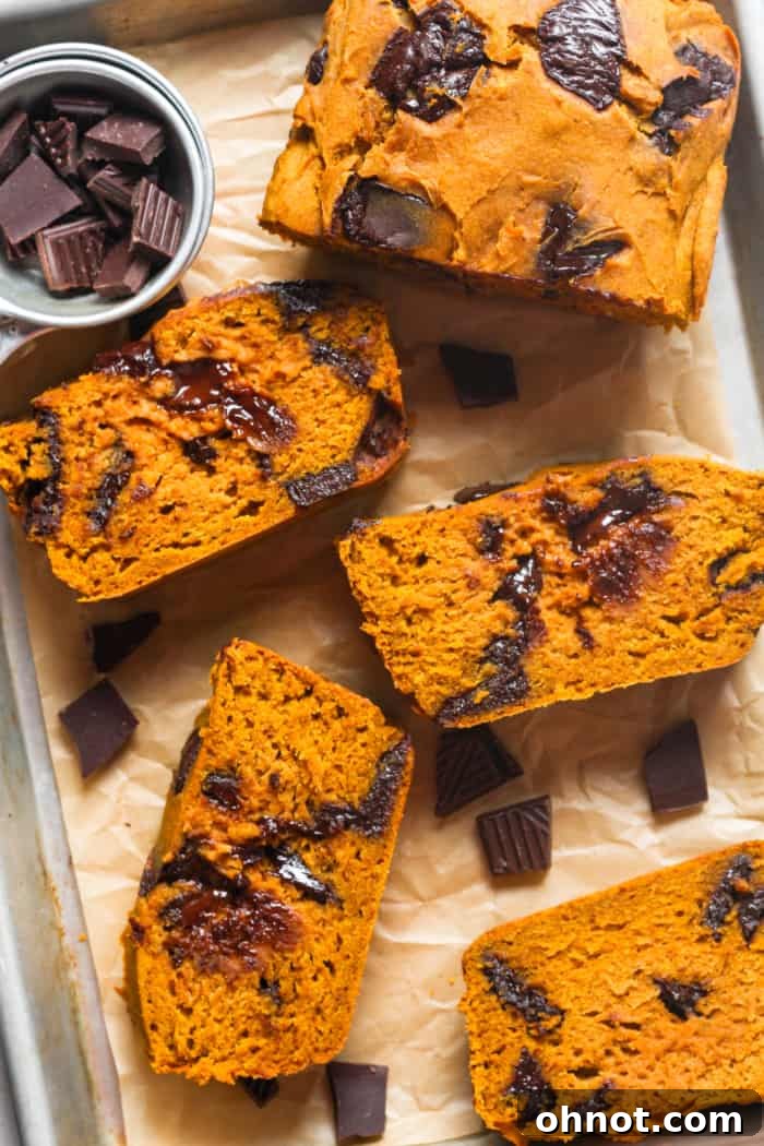 A perfectly baked loaf of pumpkin chocolate chip bread, sliced to reveal moist interior and melted chocolate chips.
