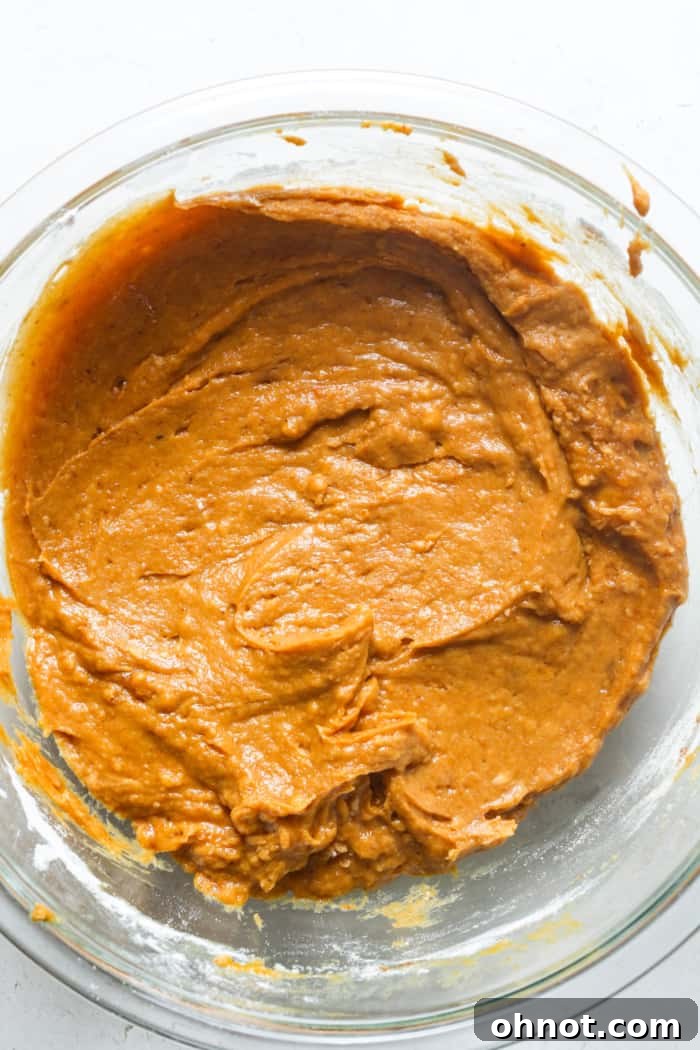 Orange bread batter with dry ingredients partially mixed.