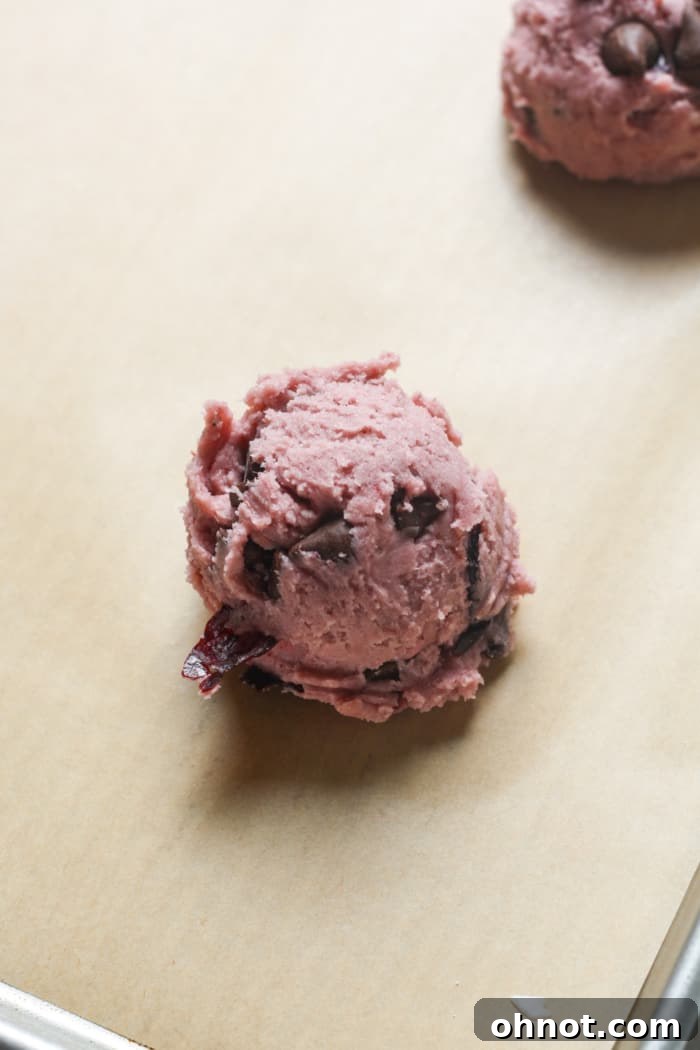 Pink cookie dough balls on a baking sheet.