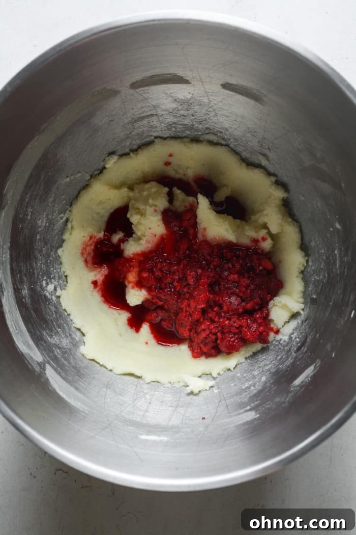 Raspberries being added to cookie dough in a mixer.