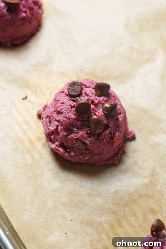Scooped pink dough ball on parchment paper.