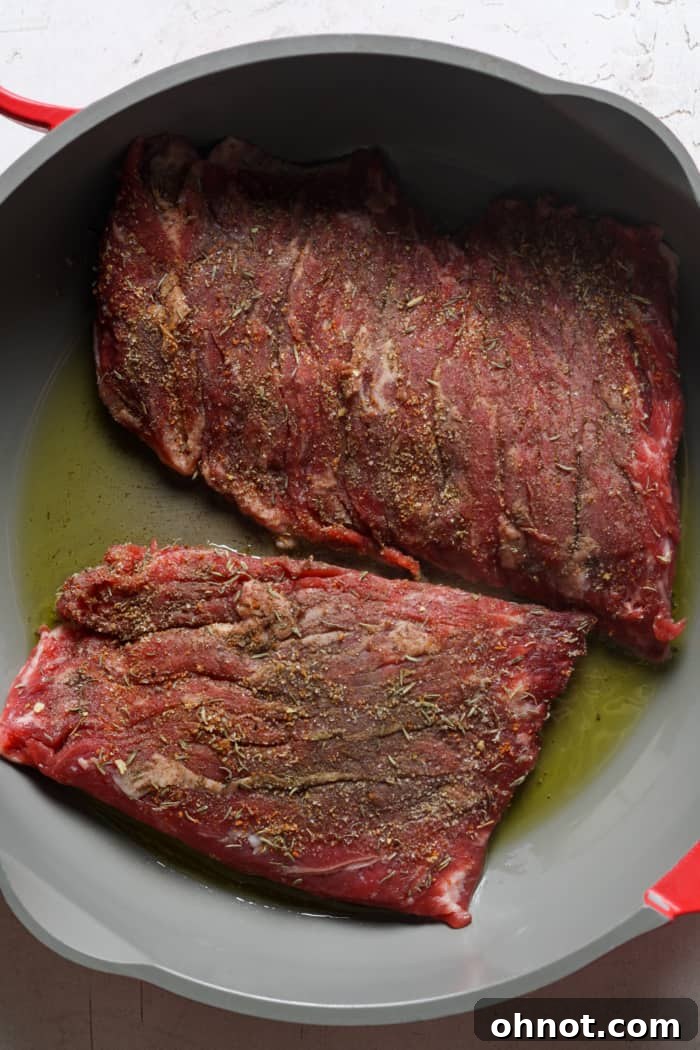 Skirt steak searing in a hot skillet with olive oil.
