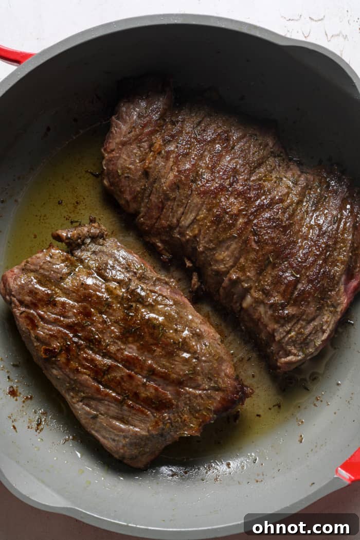 Perfectly seared skirt steak cooking in a cast iron skillet.