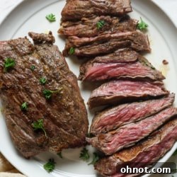 Skirt steak on a plate with fresh herbs.