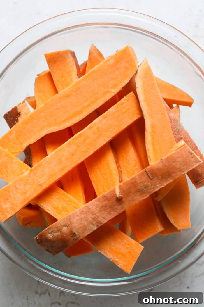 Sweet potatoes cut into uniform fries, ready for seasoning.