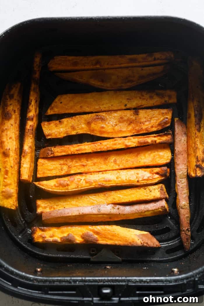 Golden, crispy air fryer sweet potato fries in the air fryer basket.