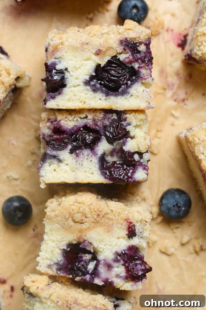 A stack of three slices of blueberry coffee cake, showcasing the moist layers and crumbly streusel.