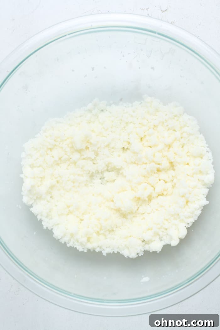 Close-up of butter and granulated sugar being creamed together in a mixing bowl with an electric mixer, forming a light and fluffy mixture.