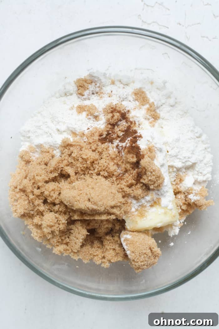 Separate bowl showing ingredients for streusel topping: brown sugar, flour, and cubes of butter before mixing.