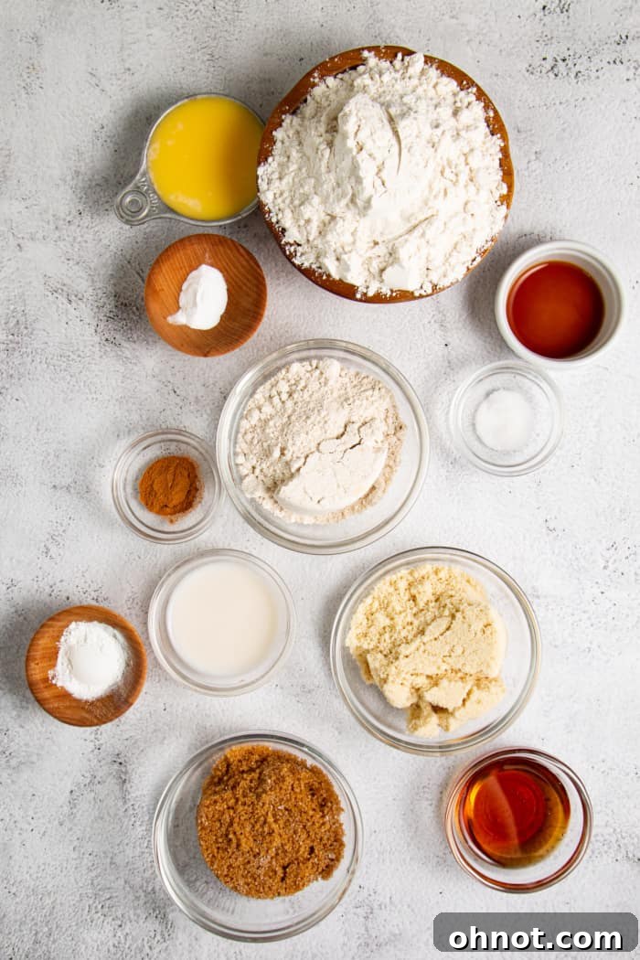 Bowls of gluten-free flours, brown sugar, and spices, alongside melted butter, maple syrup, and vanilla extract—all essential ingredients for homemade graham crackers.