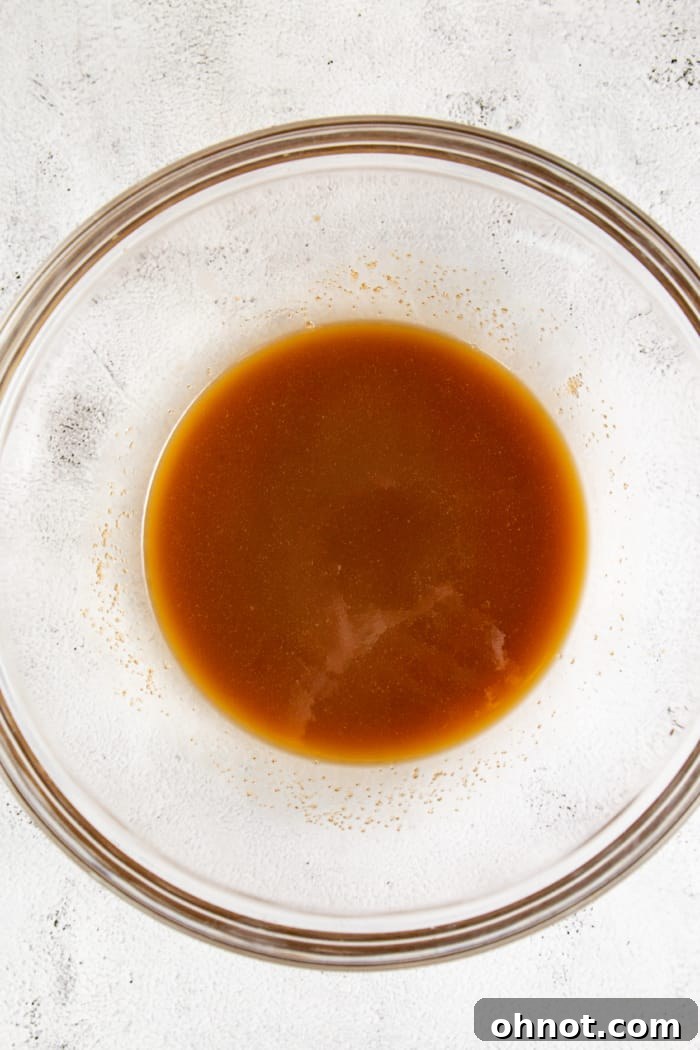 A bowl containing liquid ingredients: melted butter, maple syrup, and milk, waiting to be combined with the dry mixture.