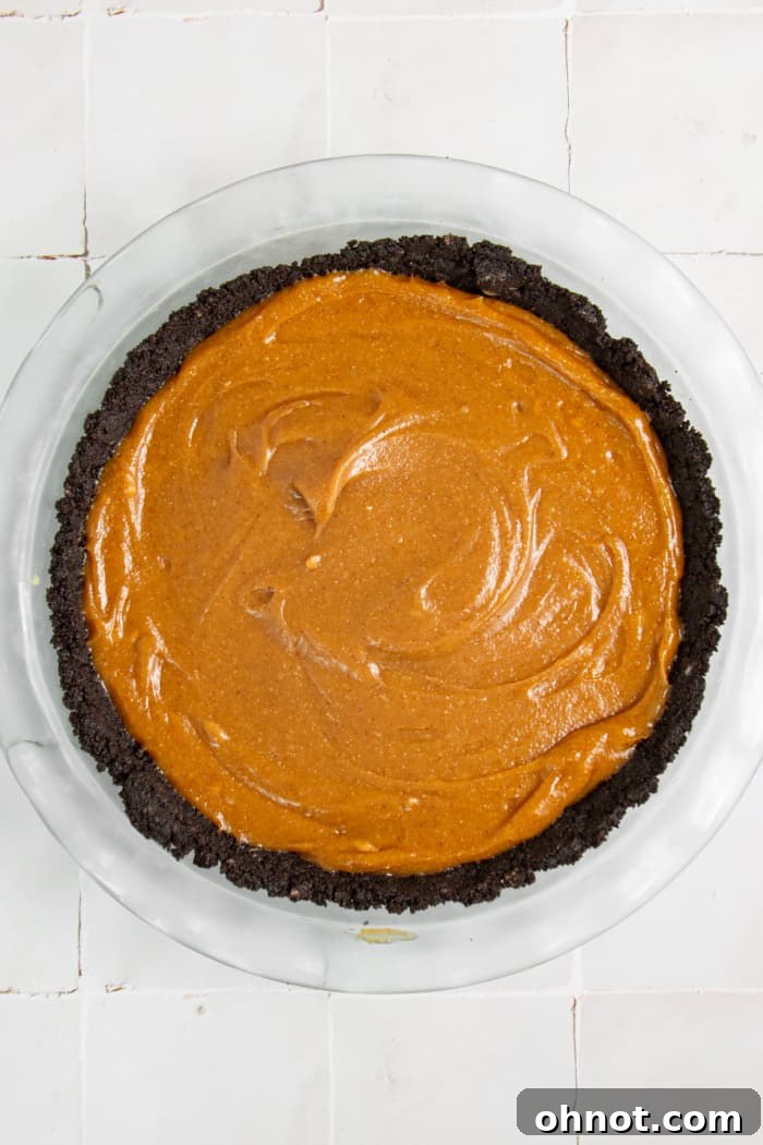 The creamy peanut butter filling spread evenly over the chocolate Oreo crust in a pie dish.