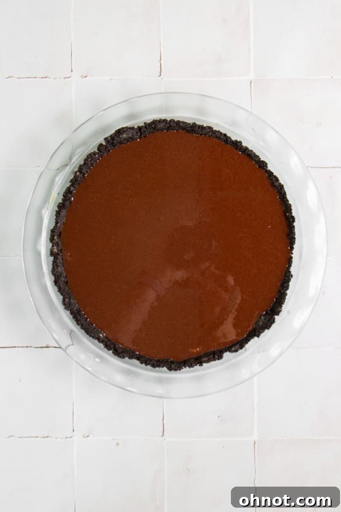 The final layer of smooth chocolate ganache spread over the peanut butter filling in the Oreo crust.