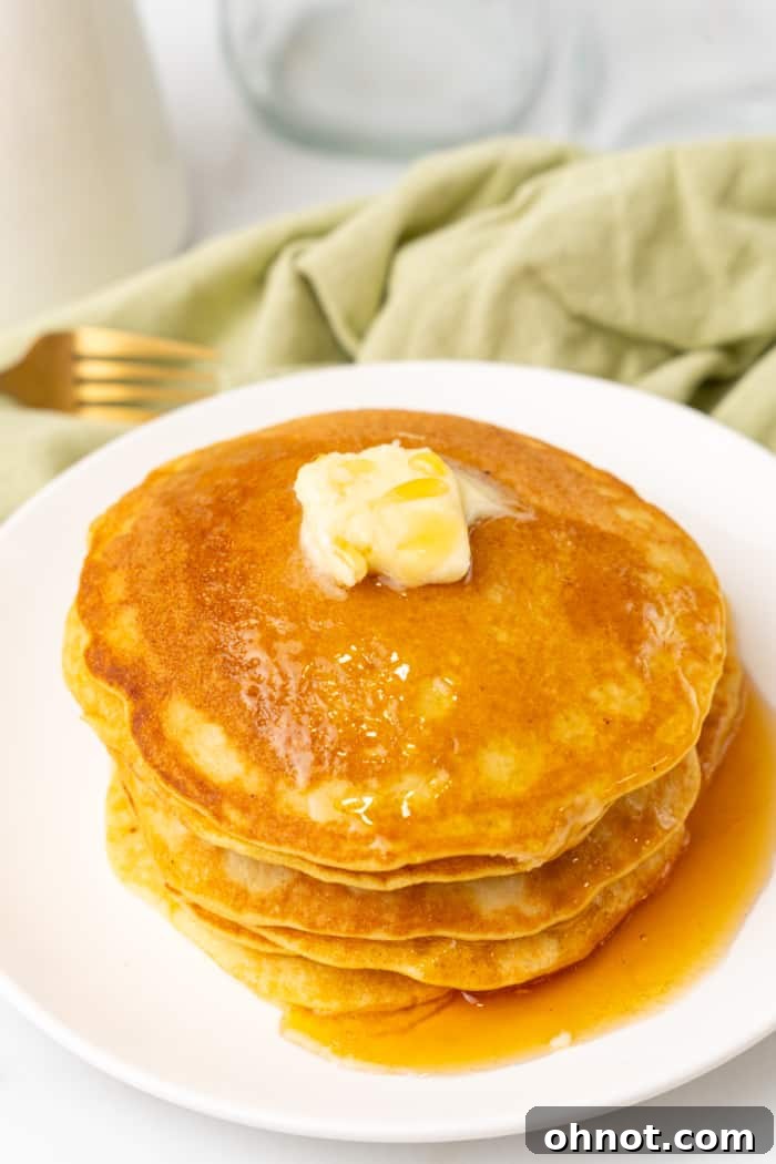 A stack of perfectly golden keto pancakes topped with fresh berries and sugar-free syrup.