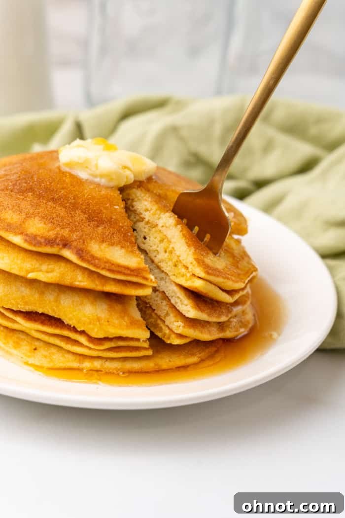 A keto pancake being cut with a fork, showing its fluffy interior.