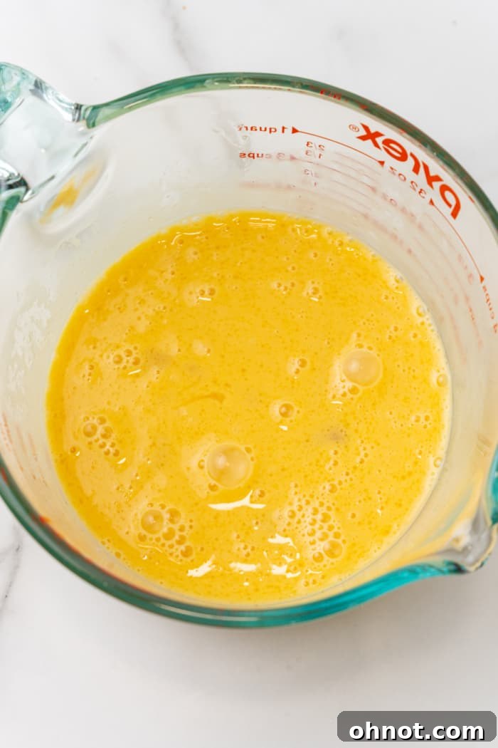 Whisked eggs in glass cup, a smooth yellow mixture.
