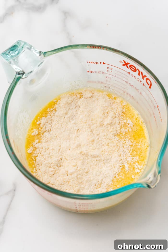 Whisked eggs with almond flour being slowly added.