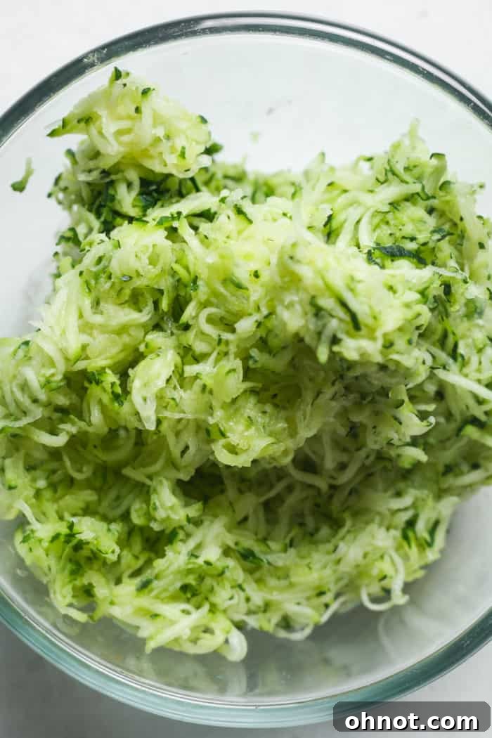 Bowl filled with freshly shredded zucchini, patted dry and ready for baking.