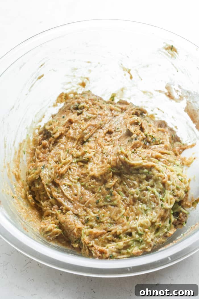 A bowl of moist zucchini bread batter, showcasing its rich texture.