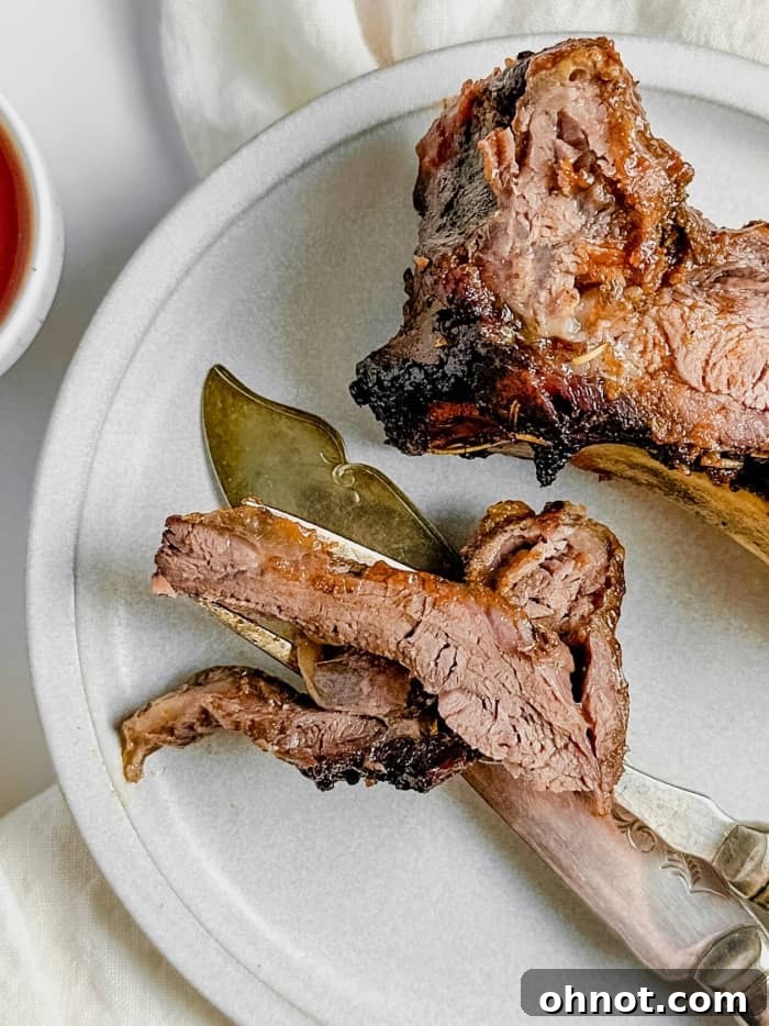 Juicy beef ribs being carved with a sharp knife, showing tender meat.