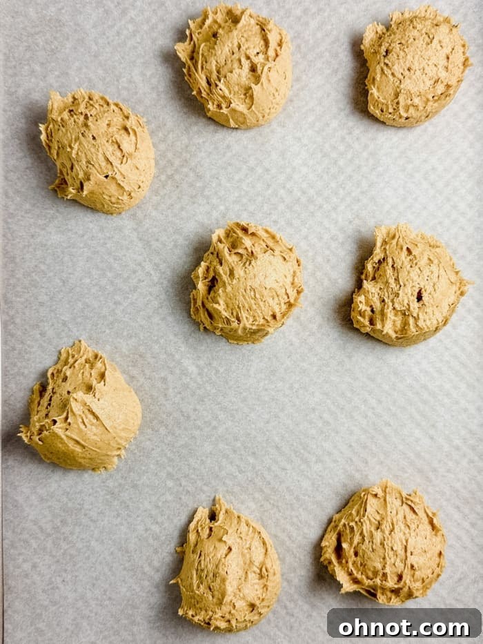 Scooped pumpkin spice cookie dough evenly spaced on a baking pan.