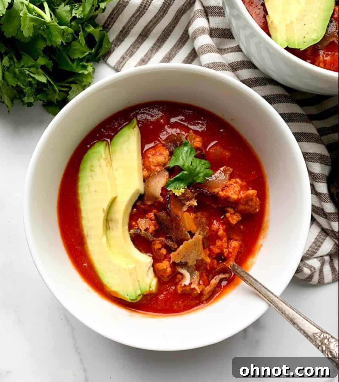 Hearty Whole30 Bacon Chili garnished with avocado in a bowl, perfect for a comforting meal.