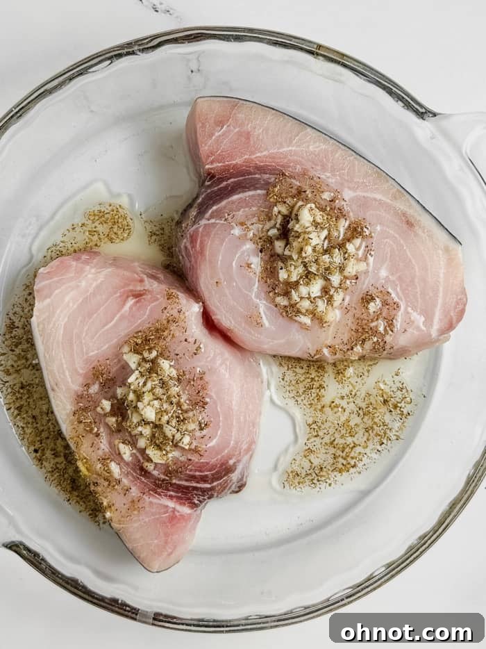 Swordfish steak soaking in the marinade in a dish.