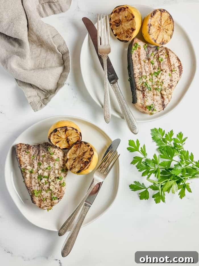 Plates with grilled swordfish, lemon, and parsley.