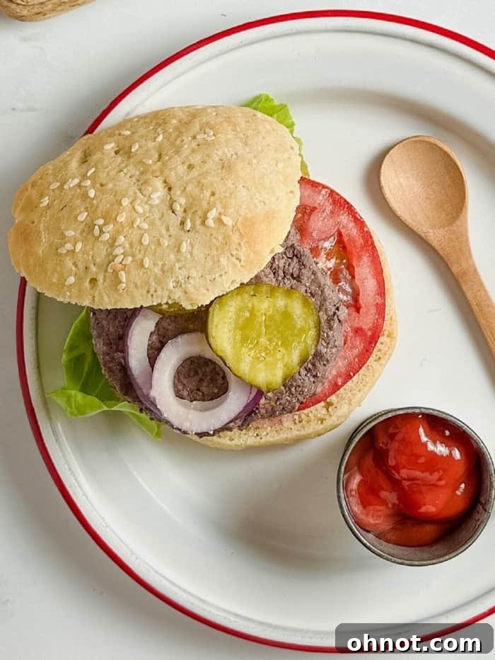 A plate featuring a delicious burger on a homemade gluten-free bun, with a side of ketchup.