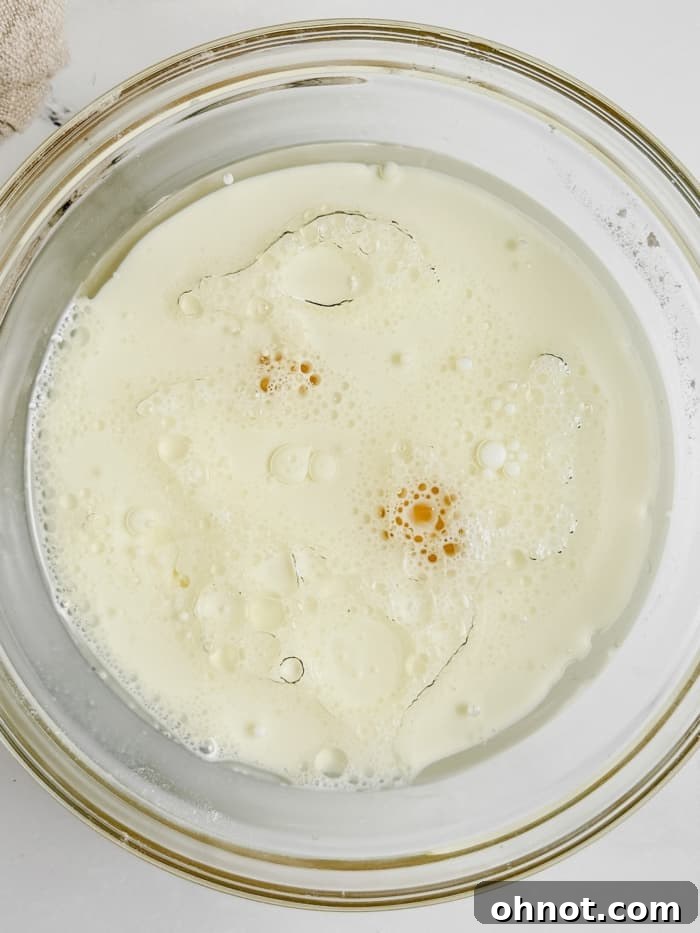 Wet ingredients for gluten-free buns: warm milk, olive oil, and eggs in a separate mixing bowl.