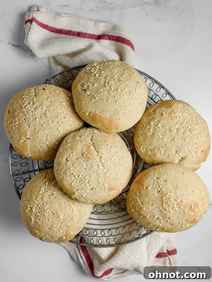 Freshly baked gluten-free hamburger buns cooling on a wire rack, perfectly golden.