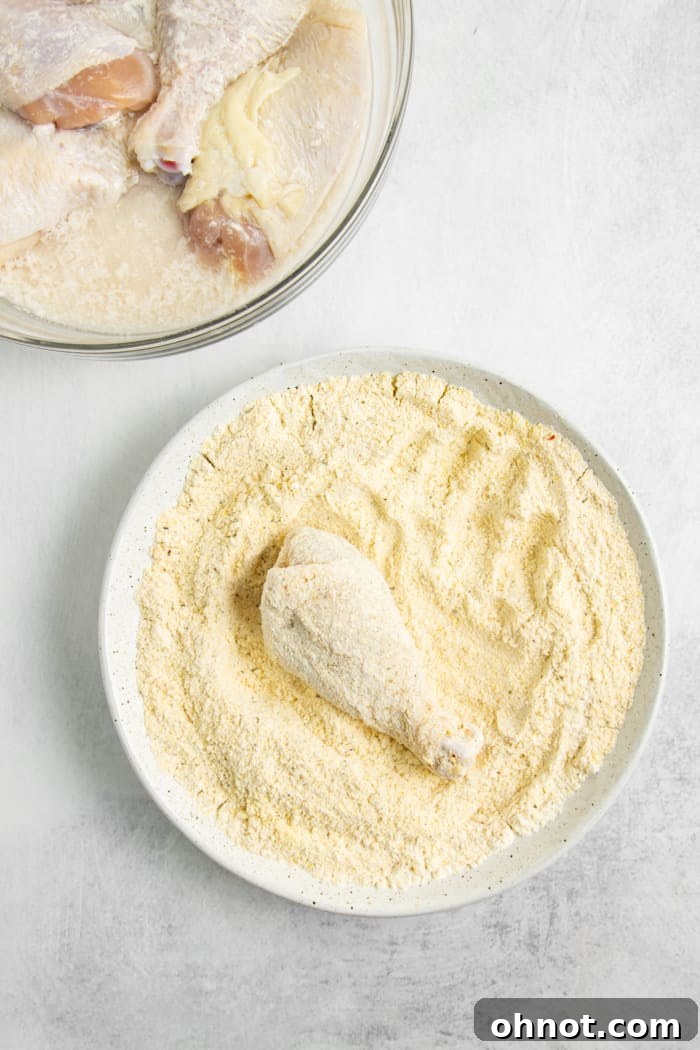 A chicken drumstick fully coated in the gluten-free breading mixture, ready for frying.
