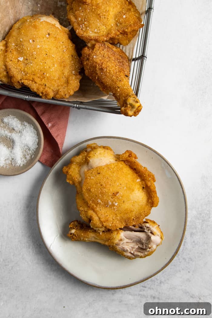 A close-up of a tender, crispy gluten-free chicken thigh, showing its juicy interior and golden breading.
