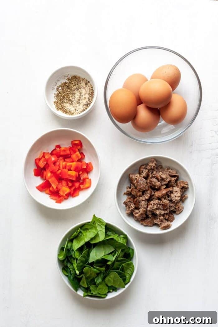 Fresh ingredients laid out for making Whole30 breakfast muffins, including vibrant spinach, red peppers, eggs, and sausage.