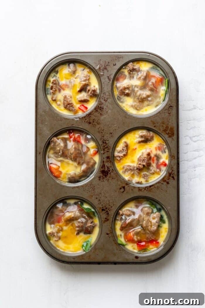 A muffin tray with Whole30 egg muffins poured into each cavity, ready to be baked to perfection.