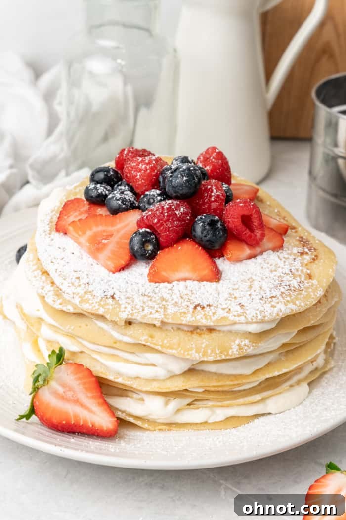 A beautifully assembled crepe cake, tall with many layers of crepes and whipped cream, ready to be sliced.