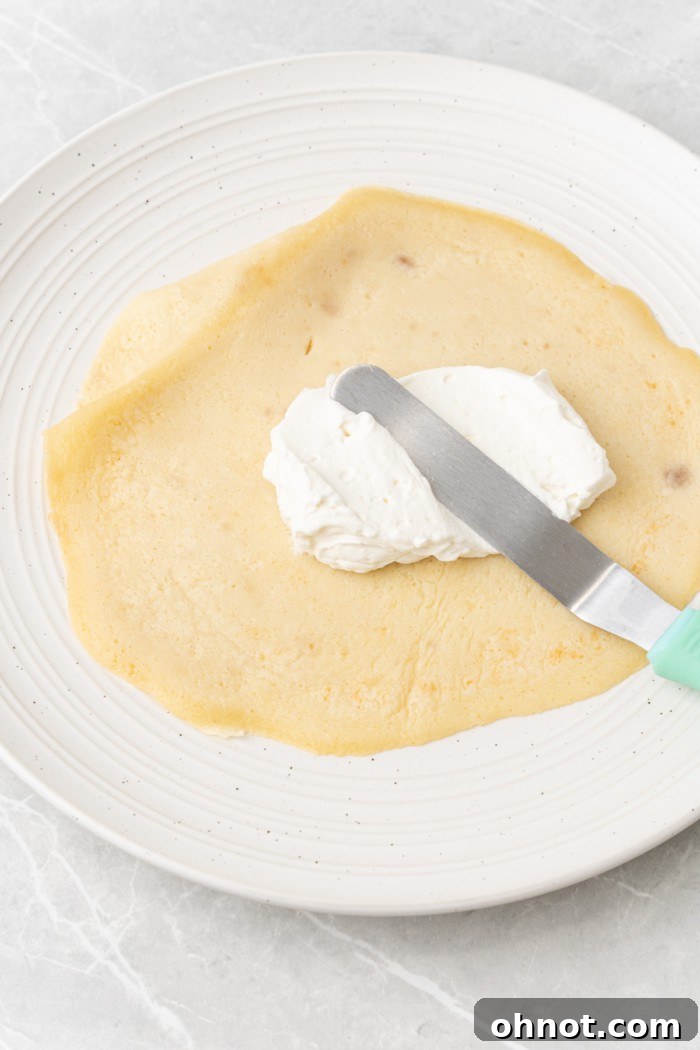 A single crepe with a thin layer of whipped cream spread evenly over its surface.