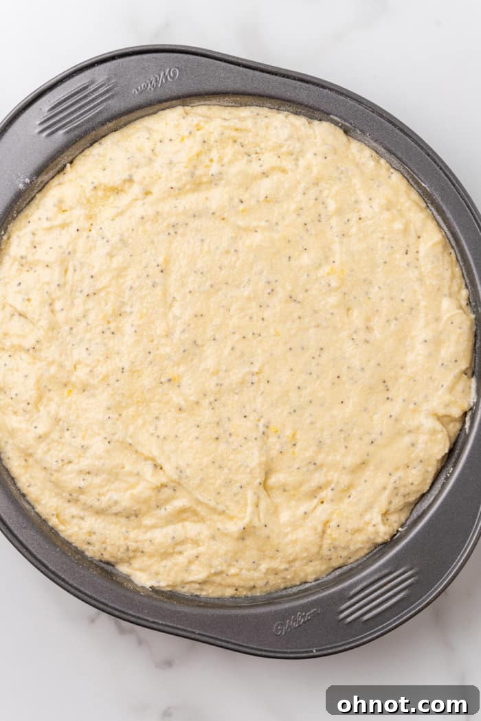 Raw lemon cake batter in a round baking pan.