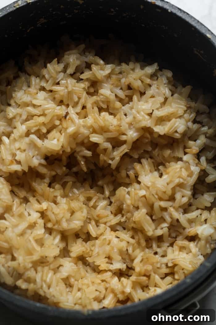 Fluffy brown rice cooking in a saucepan.
