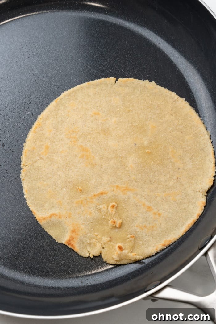 A perfectly cooked almond flour tortilla, lightly browned, resting in a skillet.