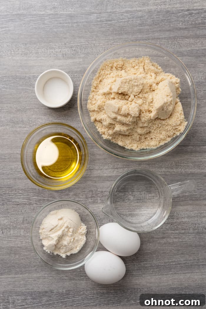 All the key ingredients for almond flour tortillas, including blanched almond flour, coconut flour, eggs, olive oil, and salt, artfully arranged on a counter.