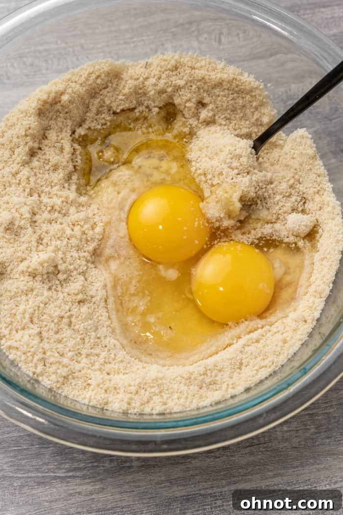 Almond flour mixed with eggs and olive oil, forming a crumbly texture in a bowl.