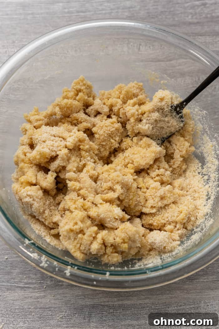 Dry, coarse dough mixture resting in a glass bowl, ready for the addition of water.