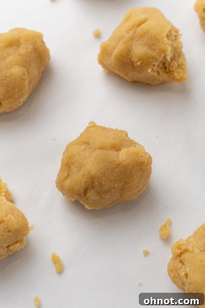 Eight perfectly portioned almond flour dough balls arranged on parchment paper, ready for rolling.