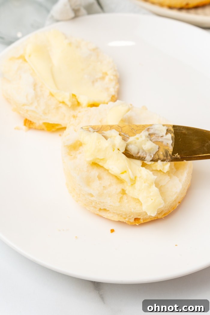 A freshly baked gluten free biscuit split open, with a pat of butter melting inside.