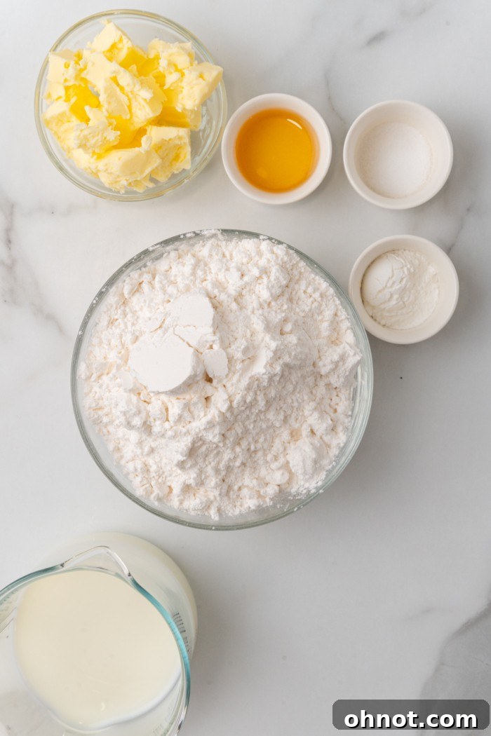 All the raw ingredients for gluten free biscuits laid out on a wooden surface, including flour, butter, and milk.