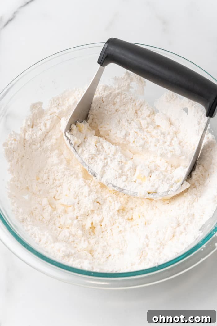 A pastry cutter being used to incorporate butter into the dry flour mixture.
