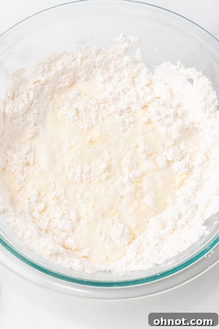 Milk mixture being poured into gluten free flour and butter in a bowl.
