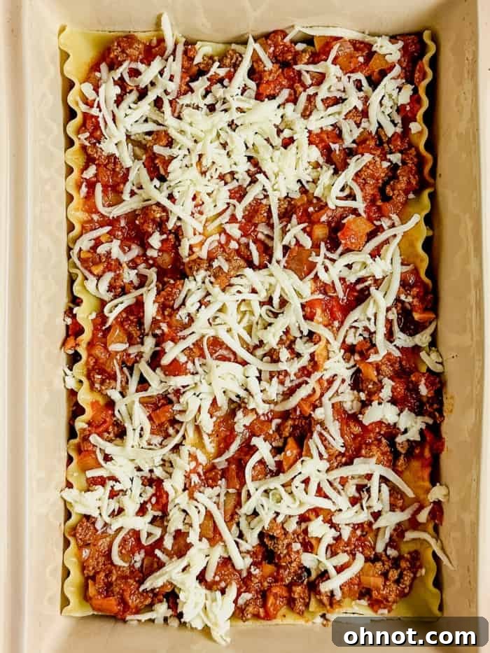 A layer of shredded mozzarella and Parmesan cheese added over the meat sauce and noodles.
